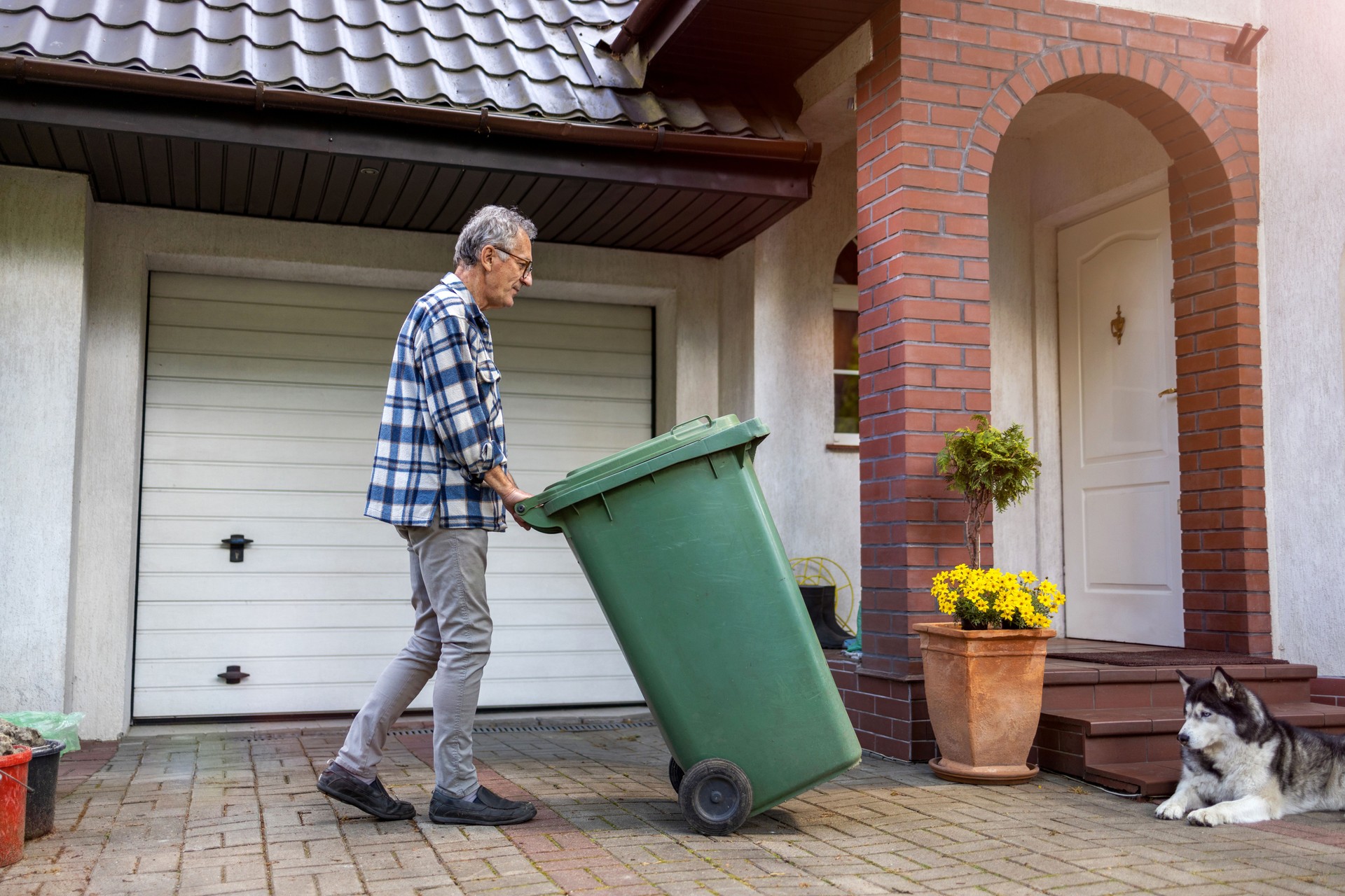 Senior man rolling garbage can